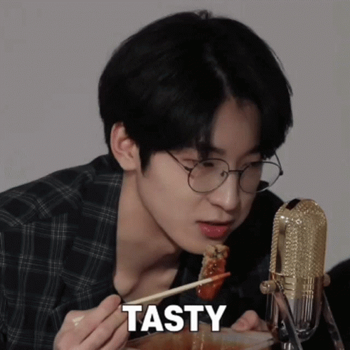 A Young Man With Glasses Is Eating Food With Chopsticks And The Word Tasty Is On The Bottom GIF