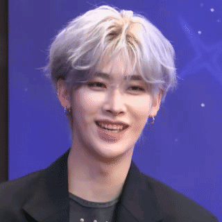 A Young Man With Gray Hair Is Smiling And Wearing A Black Jacket And Earrings . GIF
