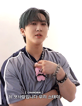 A Young Man With Green Hair Is Wearing A Necklace And Bracelets While Holding A Stuffed Animal . GIF