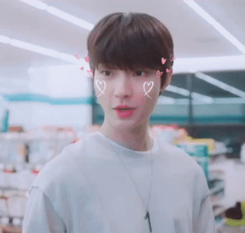 A Young Man With Hearts Drawn On His Face And A Necklace With The Number 1 On It GIF