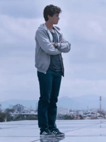 A Young Man With His Arms Crossed Stands On A Rooftop GIF