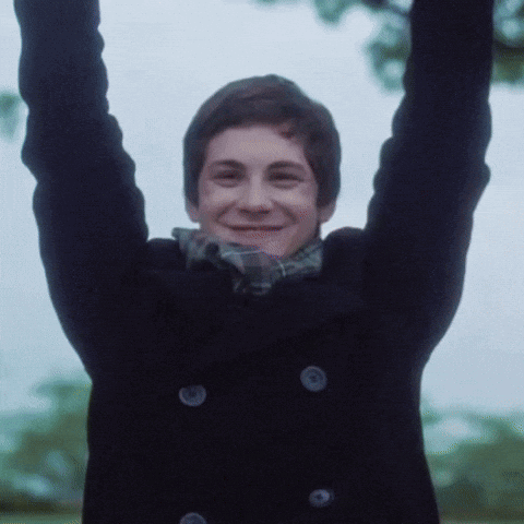 A Young Man With His Arms In The Air Is Wearing A Black Coat GIF