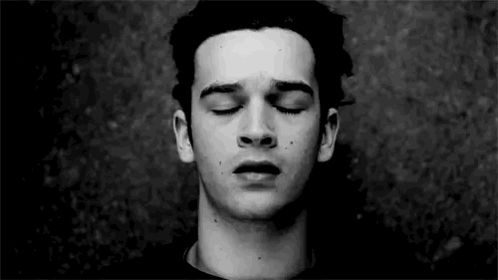 A Young Man With His Eyes Closed In A Black And White Photo . GIF