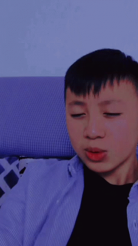 A Young Man With His Eyes Closed Is Wearing A Blue Shirt GIF