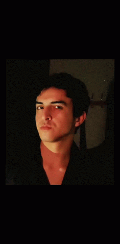 A Young Man With His Eyes Closed Looks At The Camera GIF