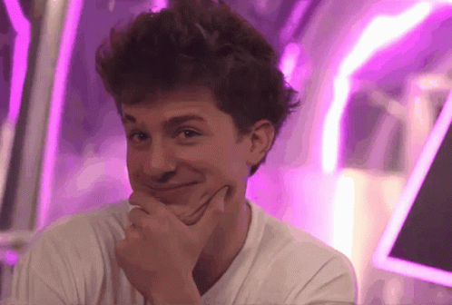 A Young Man With His Hand On His Chin Looks At The Camera GIF