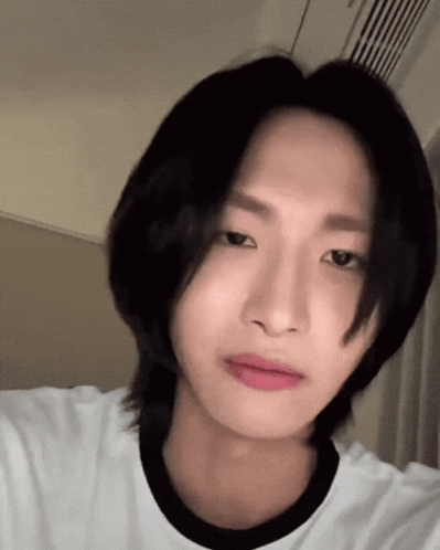 A Young Man With Long Black Hair Is Wearing A White Shirt With A Black Collar GIF