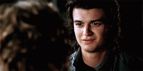 A Young Man With Long Hair Is Smiling While Looking At A Woman . GIF