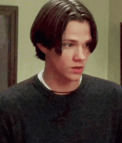 A Young Man With Long Hair Is Wearing A Black Sweater GIF