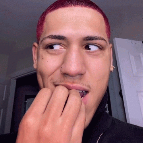 A Young Man With Red Hair And A Nose Ring Is Biting His Nails GIF