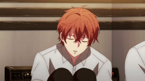 A Young Man With Red Hair Is Sitting With His Eyes Closed GIF