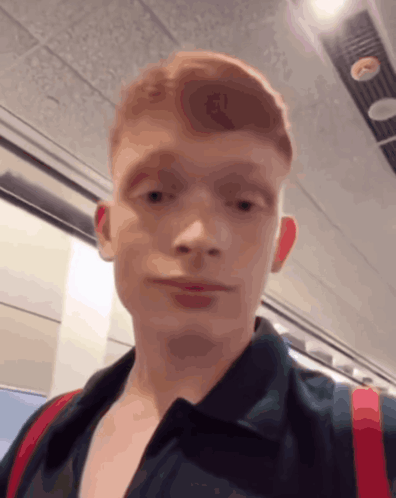 A Young Man With Red Hair Is Wearing A Black Shirt GIF