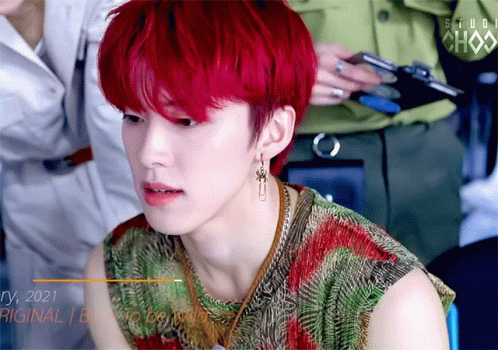 A Young Man With Red Hair Is Wearing Earrings And A Shirt That Says Studio Chax GIF