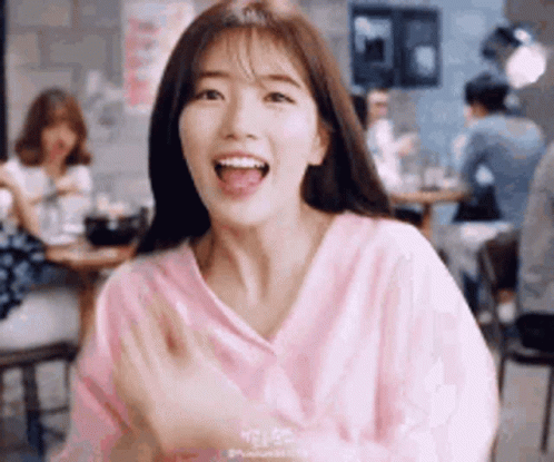A Young Woman In A Pink Sweater Is Sitting At A Table In A Restaurant . GIF