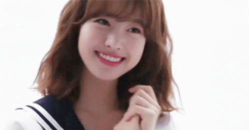 A Young Woman In A Sailor Suit Is Smiling And Holding Her Hands Together . GIF