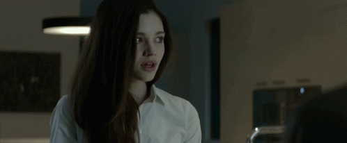 A Young Woman In A White Shirt Is Talking To A Man In A Kitchen . GIF