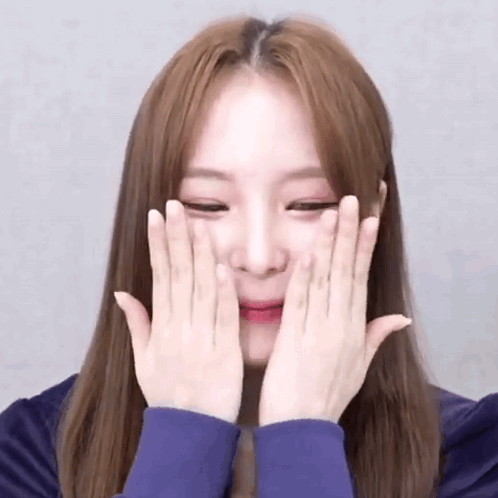 A Young Woman Is Covering Her Face With Her Hands . GIF
