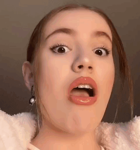 A Young Woman Is Making A Funny Face With Her Mouth Open . GIF