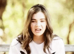 A Young Woman Is Sitting On A Bench With Her Mouth Open . GIF