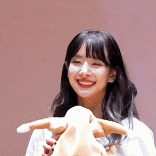 A Young Woman Is Smiling While Holding A Stuffed Animal . GIF