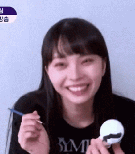 A Young Woman Is Smiling While Holding A Toy And A Spoon In Her Hand . GIF