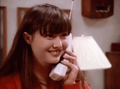 A Young Woman Is Smiling While Talking On A Cell Phone . GIF