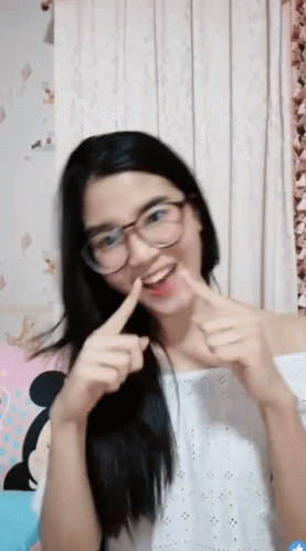 A Young Woman Wearing Glasses And A White Top Is Making A Funny Face GIF