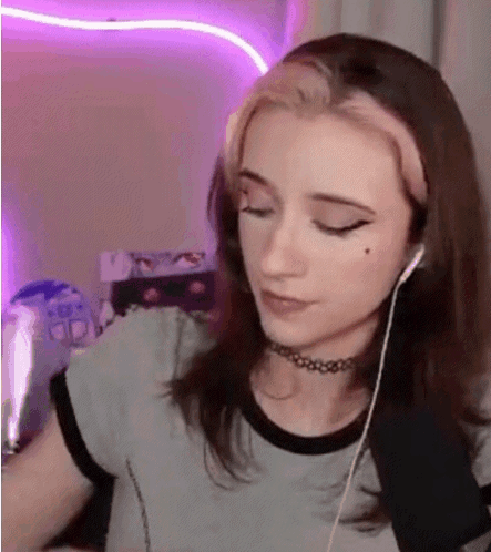A Young Woman Wearing Headphones And A Choker Is Sitting In Front Of A Computer . GIF