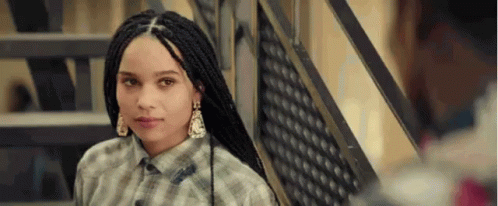 A Young Woman With Braids Is Standing Next To A Set Of Stairs . GIF
