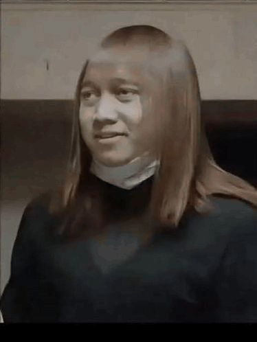 A Young Woman With Long Hair Is Wearing A Black Sweater And A White Collar . GIF