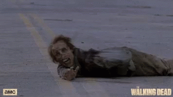 A Zombie Is Laying On The Ground With A Walking Dead Logo In The Background GIF