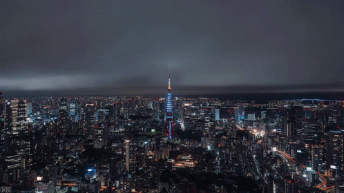 Aerial View Of City At Night With Blue Skyscraper GIF