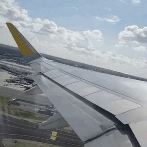 Airplane Wing with Yellow Tail Over Runway
