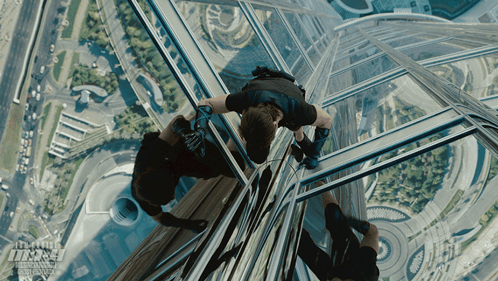 An Advertisement For Mission Impossible Shows A Man Hanging From A Building GIF