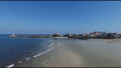 An Aerial View Of A Beach With Buildings In The Distance GIF