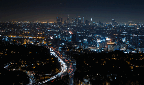 An Aerial View Of A City At Night With A Highway In The Foreground And The City Skyline In The Background GIF