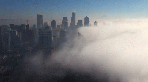 An Aerial View Of A City Skyline Covered In Clouds GIF