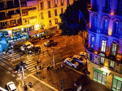 An Aerial View Of A City Street At Night With Cars Parked On The Side Of The Road GIF