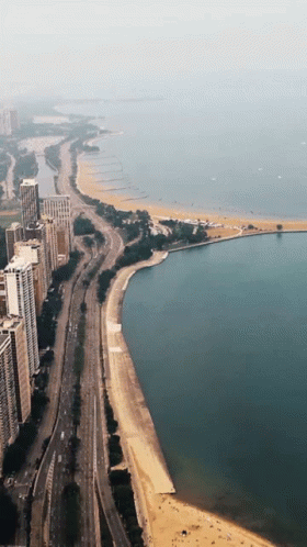 An Aerial View Of A City With A Beach And A Lake GIF