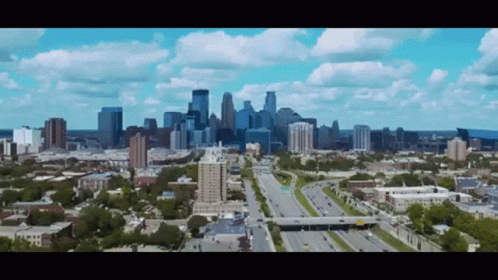 An Aerial View Of A City With A Highway In The Foreground And The Skyline In The Background GIF