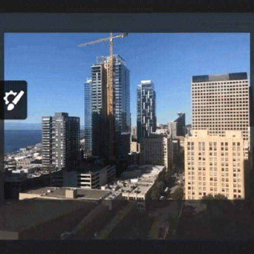 An Aerial View Of A City With A Large Crane In The Distance GIF