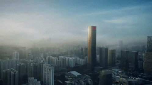 An Aerial View Of A City With A Very Tall Building In The Foreground GIF
