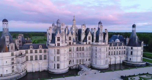 An Aerial View Of A Large White Castle With A Purple Sky In The Background GIF