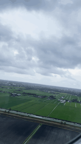 An Aerial View Of A Lush Green Field With A Cloudy Sky In The Background GIF
