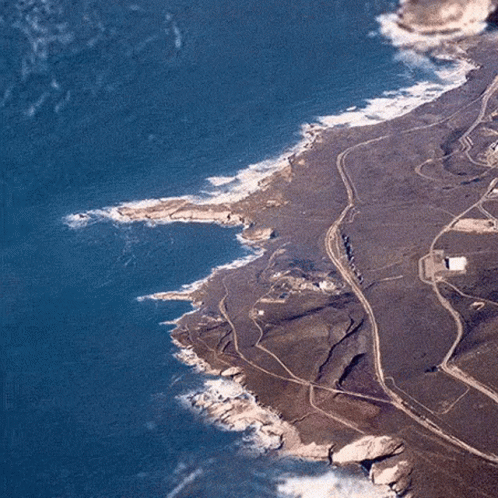 An Aerial View Of A Rocky Coastline With A Road Going Through It And A Body Of Water . GIF