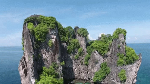 An Aerial View Of A Rocky Island In The Middle Of The Ocean . GIF