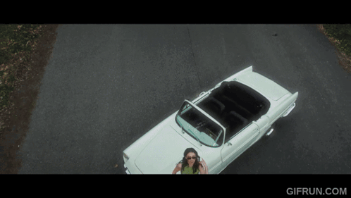 An Aerial View Of A Woman In A White Convertible With Gifrun.com Written Below It GIF