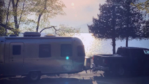 An Airstream Trailer Is Parked Next To A Black Truck GIF