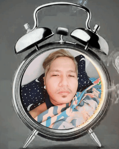 An Alarm Clock With A Man Laying In It GIF