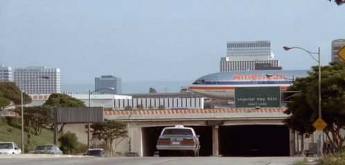 An American Airlines Airplane Is Flying Over A Highway GIF